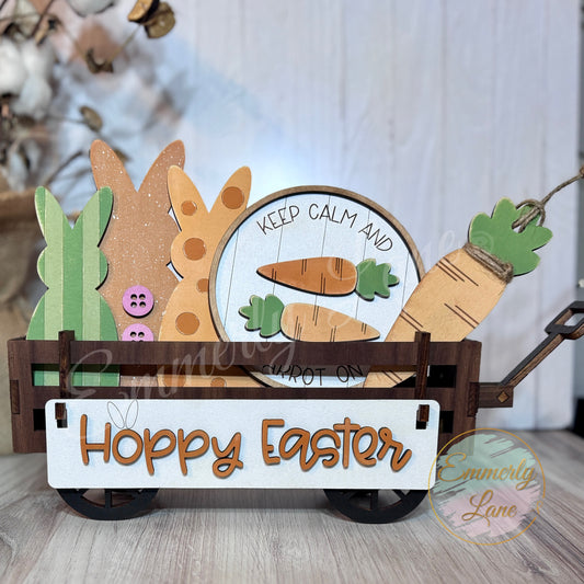 A handcrafted wooden Easter shelf sitter kit featuring a banner with the text 'Hoppy Easter', a round sign, a carrot, and three bunnies attached together, displayed in a wagon.