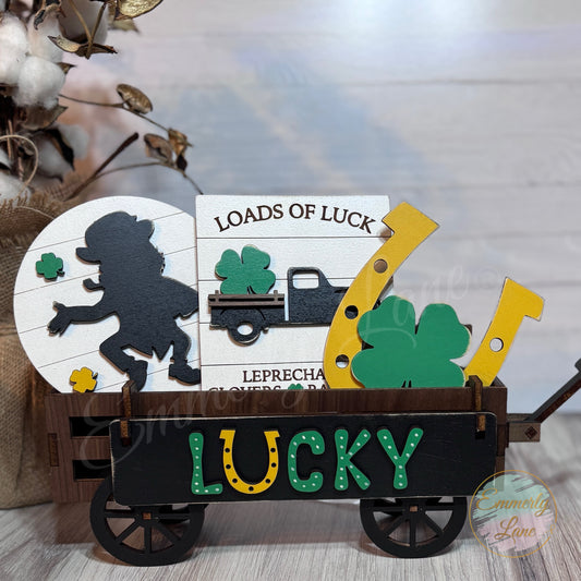 Handcrafted wooden shelf sitter with a 'Lucky' horseshoe and a wagon prop, decorated for St. Patrick's Day with green and yellow colors and a 'LOADS OF LUCK' sign.