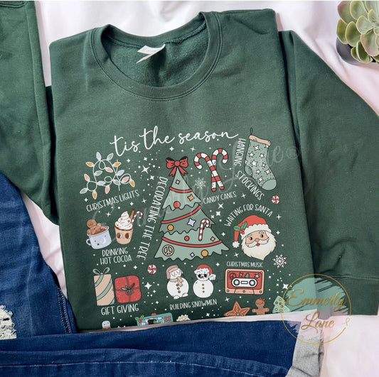 Green t-shirt with Christmas-themed graphics and text on a white background. Featuring a central Christmas tree surrounded by festive activities and items—like "Decorating the Tree," "Christmas Lights," "Baking Cookies," and "Waiting for Santa"—it's the perfect top for everyone who loves holiday cheer.